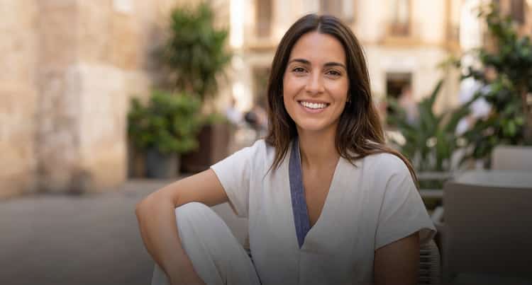 Mujer joven sonriendo con naturalidad en una terraza de Valencia, transmitiendo confianza y bienestar tras sus tratamientos dentales en Odéntitus.