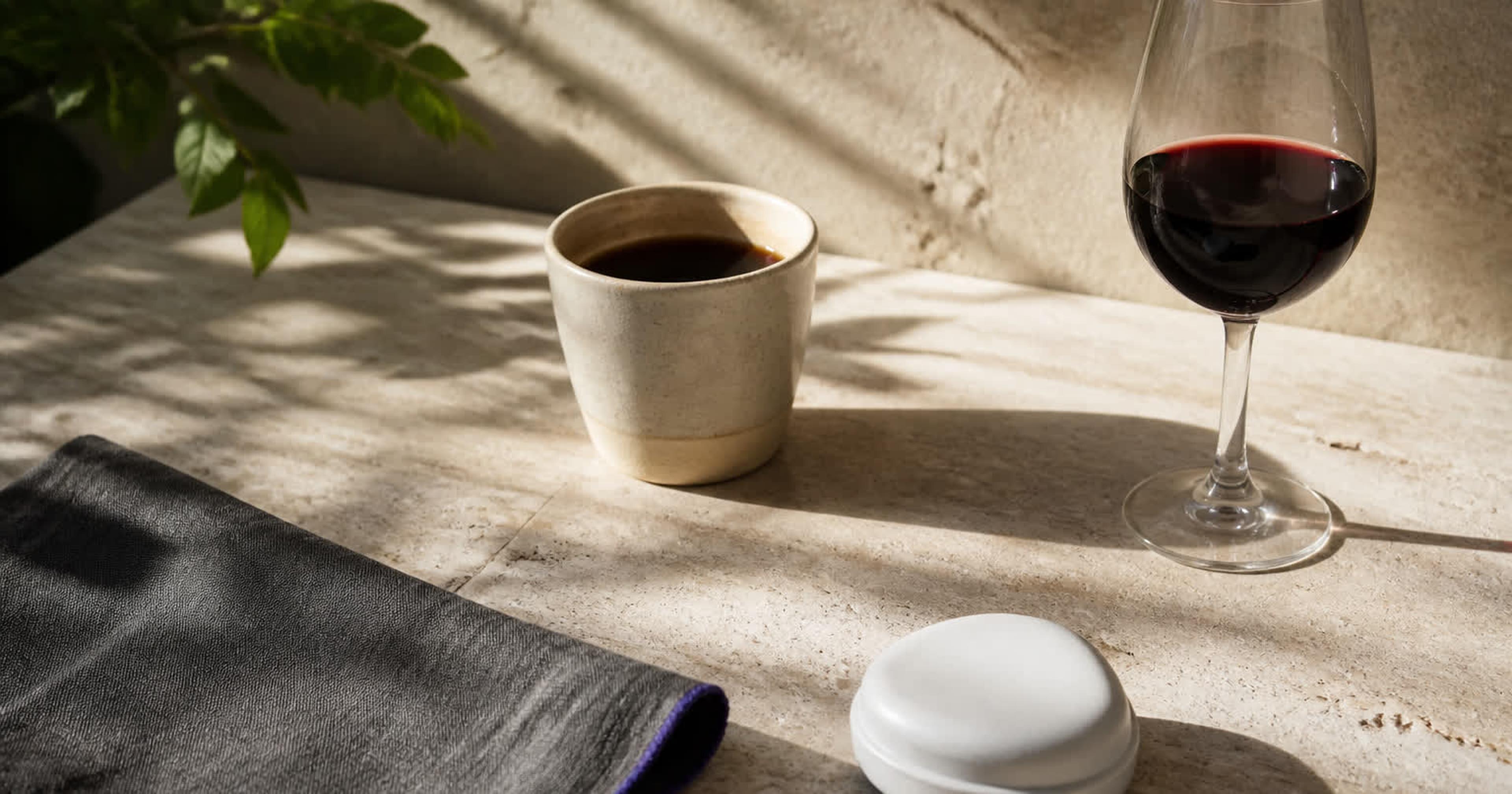 Mesa con taza de café, copa de vino, seda dental y una férula de estudio sobre mantel claro